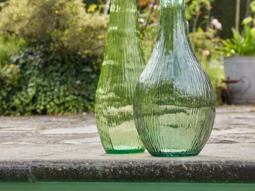 Prensik groene glazen vloervaas 75 cm met slank silhouet en geribbelde afwerking, buiten in de tuin gezet