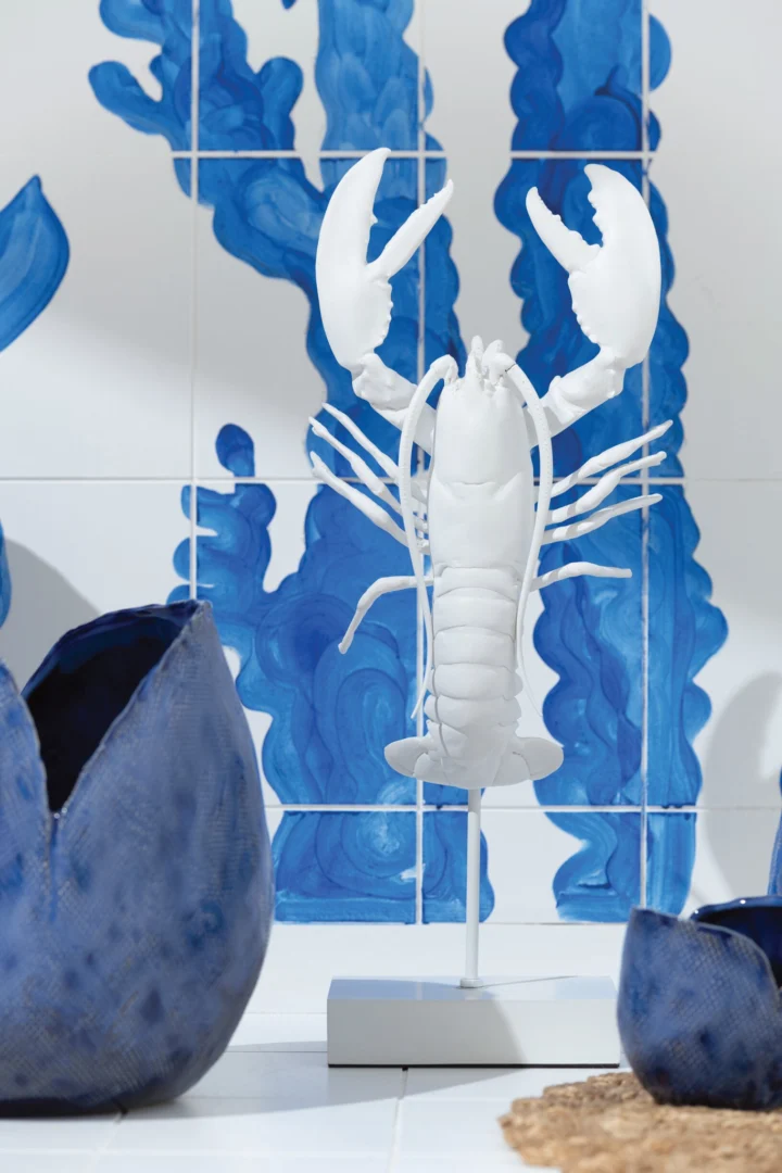 Witte kreeftvormige vaas op standaard voor blauw getegelde wand, met organische armen en scharen