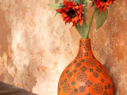 Vaas Sissora porselein oranje 35 cm met bloemprint, gevuld met rode zonnebloemen op houten tafel