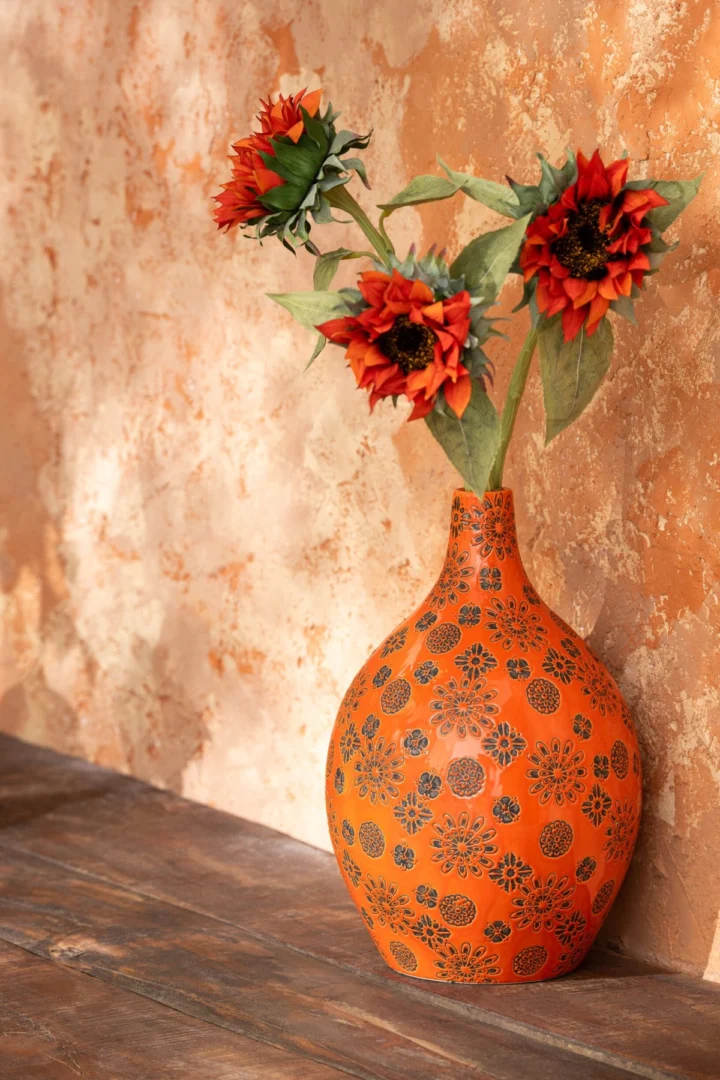 Vaas Sissora porselein oranje 35 cm met bloemprint, gevuld met rode zonnebloemen op houten tafel