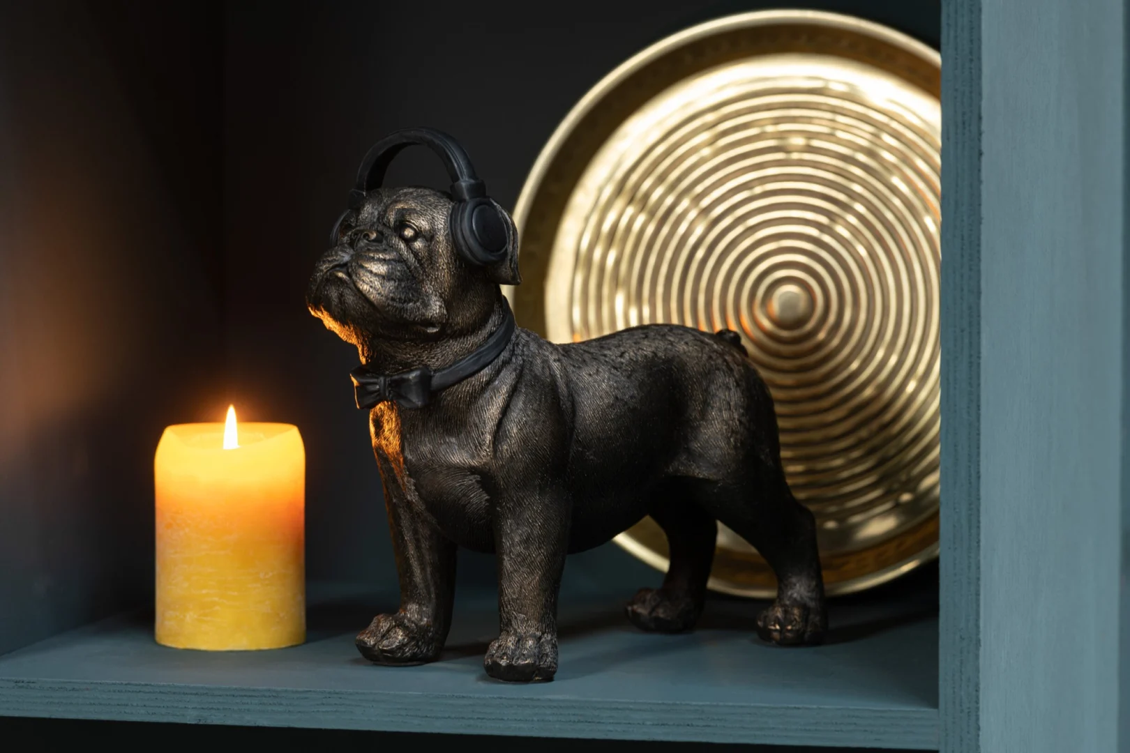 Cilinderkaars Sluvio Geel brandend op sfeervolle plank naast decoratieve hondensculptuur en gouden schaal