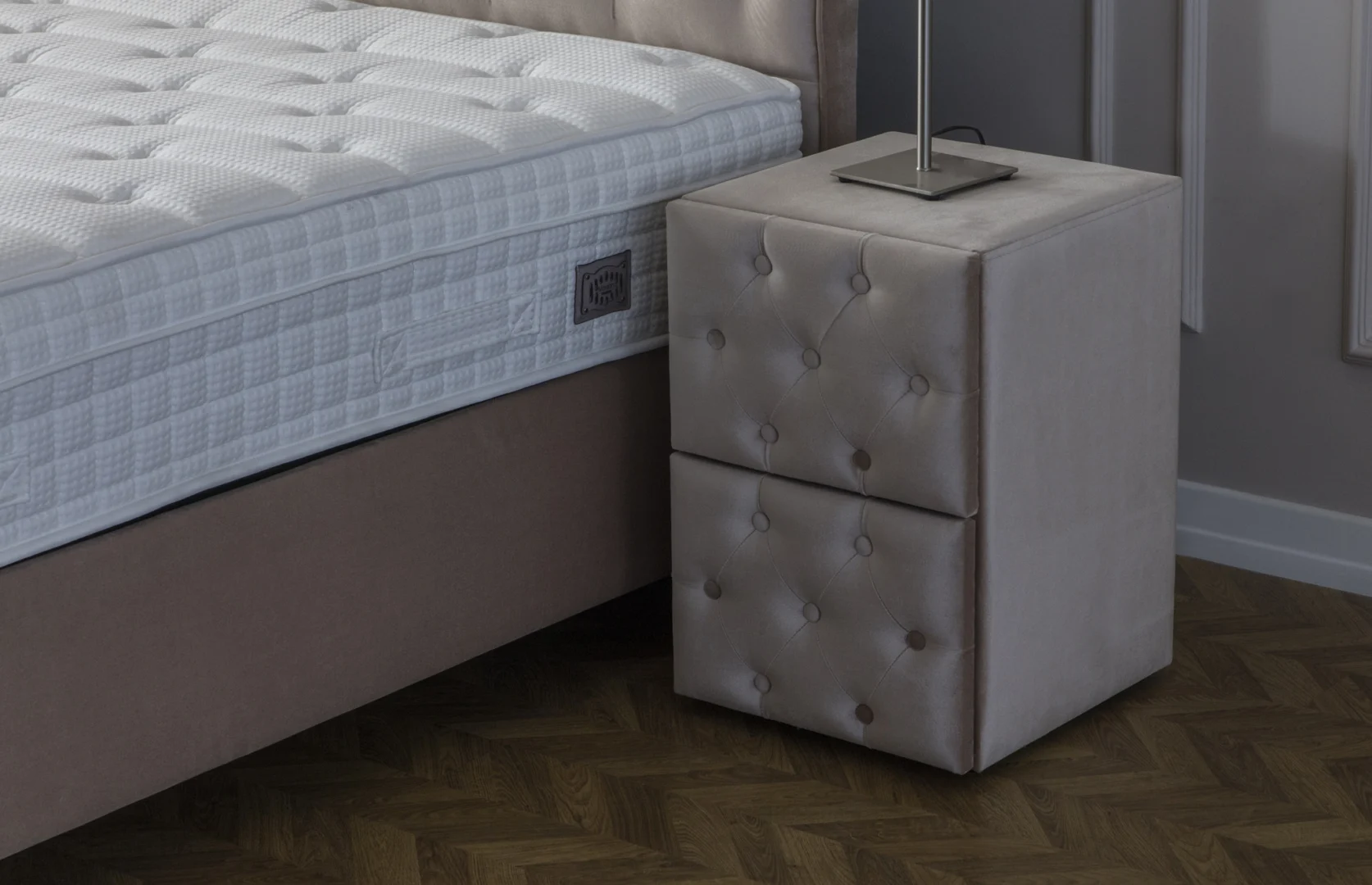 Nachtkastje Nautone beige met gestoffeerde, gecapitonneerde lades naast een bed in een rustige slaapkamer