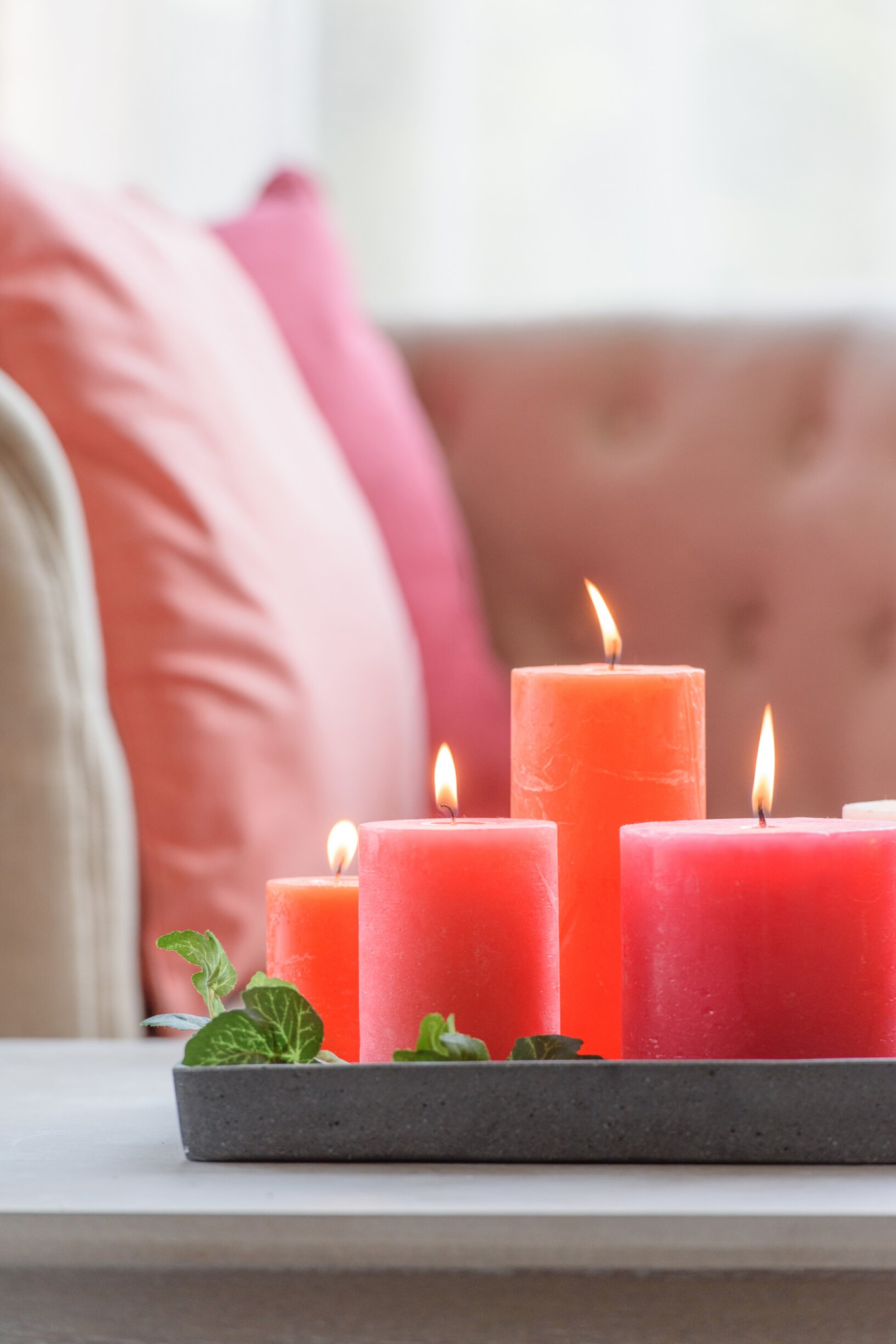Brandende roze cilinderkaars Klooka in een decoratieve schaal, sfeervol op tafel met zachte woonaccessoires