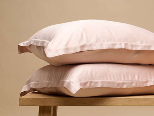 Kussenhoes Sicilie 50x60 cm in zacht roze bamboe, ademend en fris op een houten bankje