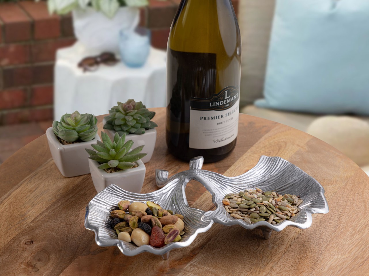 Schaal Killa aluminium zilver in ginkgo-vorm, decoratief gevuld met noten en zaden op tafel