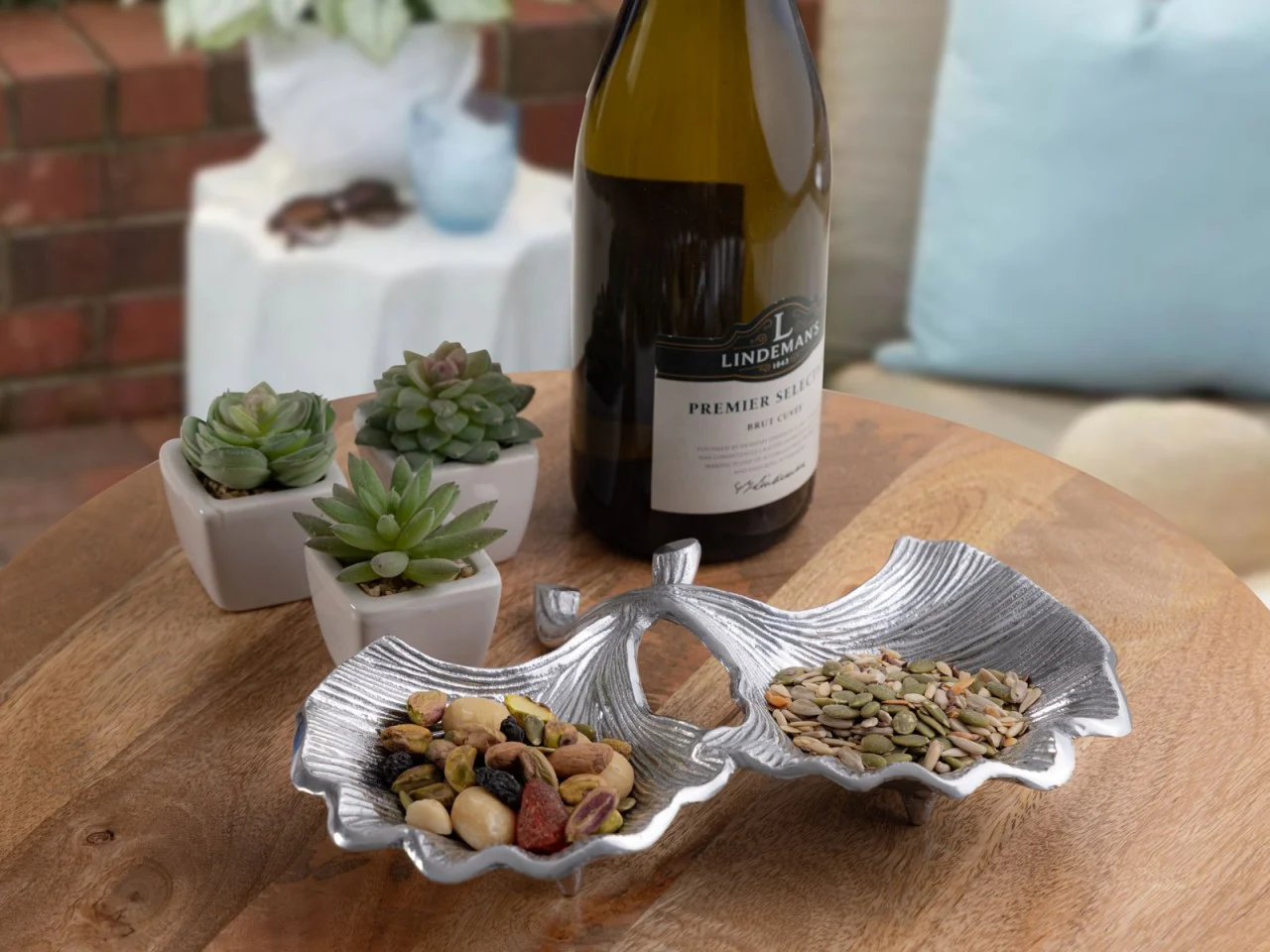 Schaal Killa aluminium zilver in ginkgo-vorm, decoratief gevuld met noten en zaden op tafel