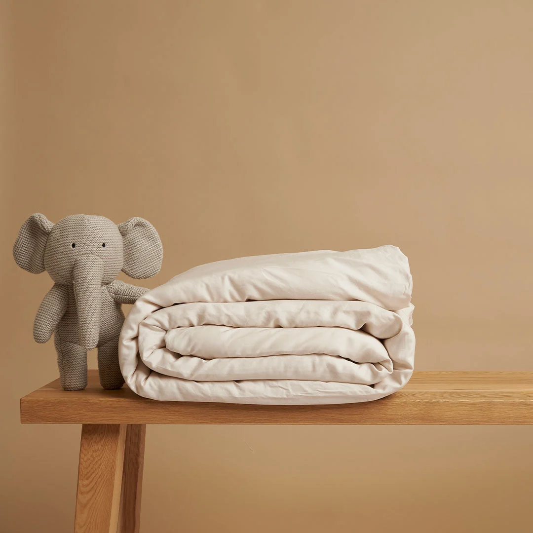 Dekbedovertrek Joorraro Beige van Tencel, zacht en ademend, naast een knuffel op een houten tafel