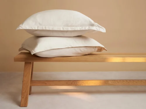 Kussenhoes Menaam beige 80x80 cm van Tencel, zacht en mat, stijlvol op een houten bankje