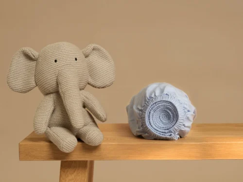 Floltil lichtblauw Tencel hoeslaken opgevouwen naast knuffelolifant, zacht en ademend voor kinderbed