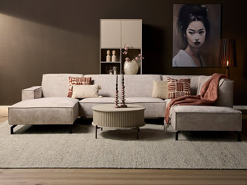 Divan Greldira Roest hoekbank met lounge links, divan rechts en zachte beige bekleding in warm modern interieur