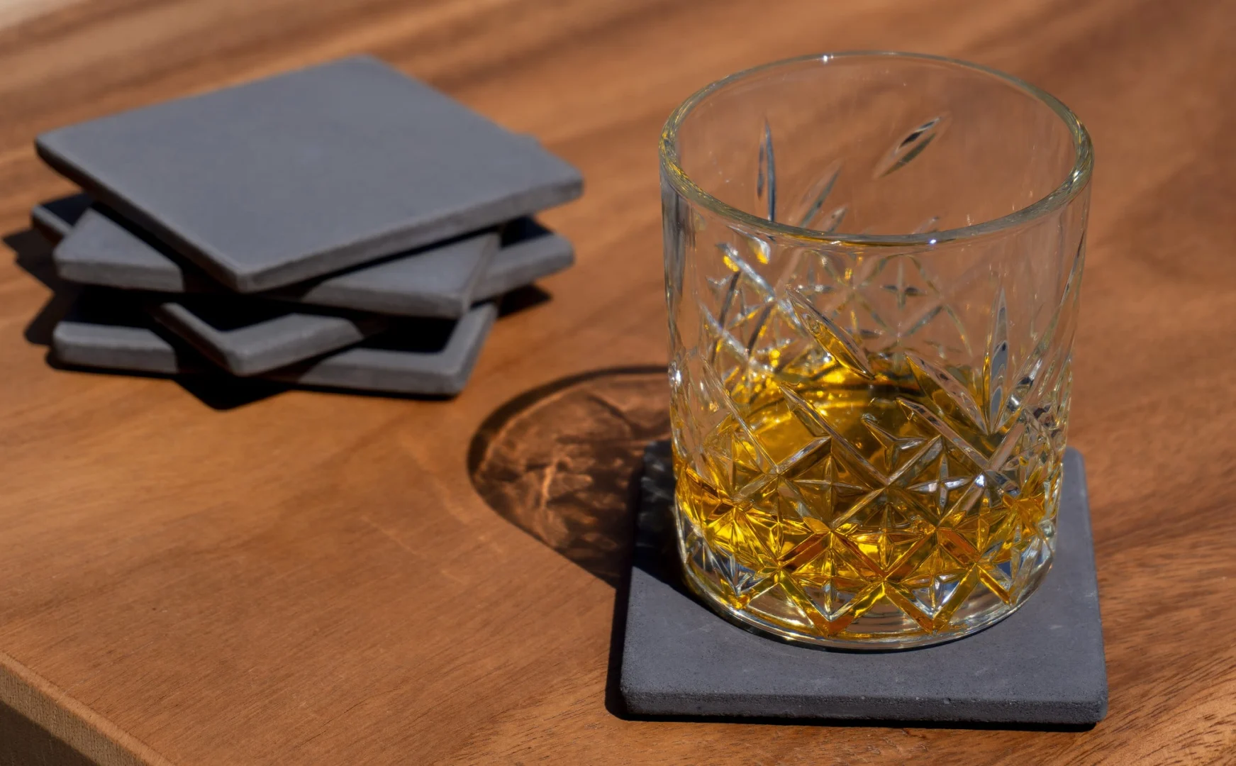 Onderzetter Brolil Beton set van 3, handgemaakte betongrijze coasters onder een glas op houten tafel