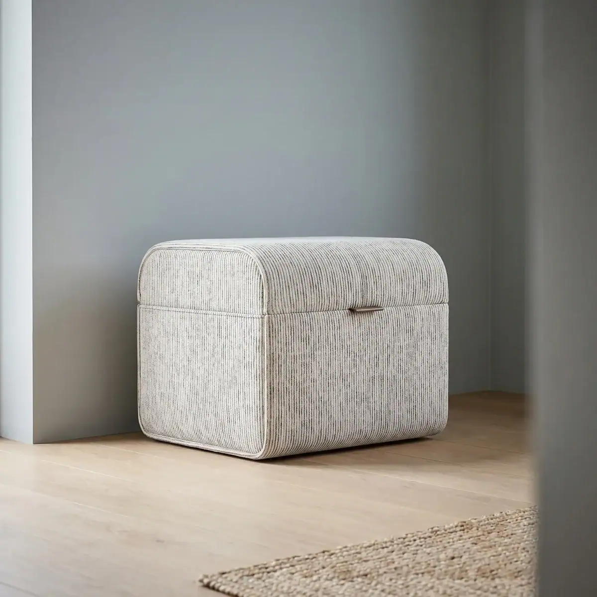 Poef Eldarsiena van Domkapa met licht gestreepte bekleding, afgeronde vorm en compact ontwerp