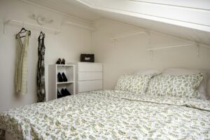 Kleine slaapkamer met bed onder het raam en een witte ladekast