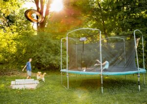 Twee kinderen spelen op een trampoline met veiligheidsnet in de tuin