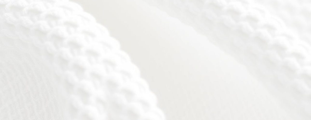 Close-up van witte boucle stof met kenmerkende lussen en textuur in een neutrale setting.