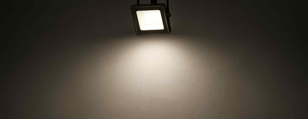 Een vierkante spot verlicht een donkere muur. Het licht is helder en wit. Het design is modern en minimalistisch. Comfortabele verlichting.