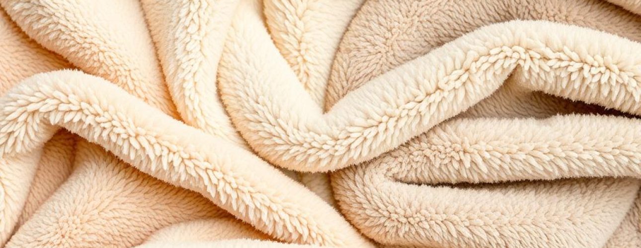 Teddy stof in verschillende kleuren, met een zachte en pluizige textuur, uitgestald op een vlakke ondergrond.