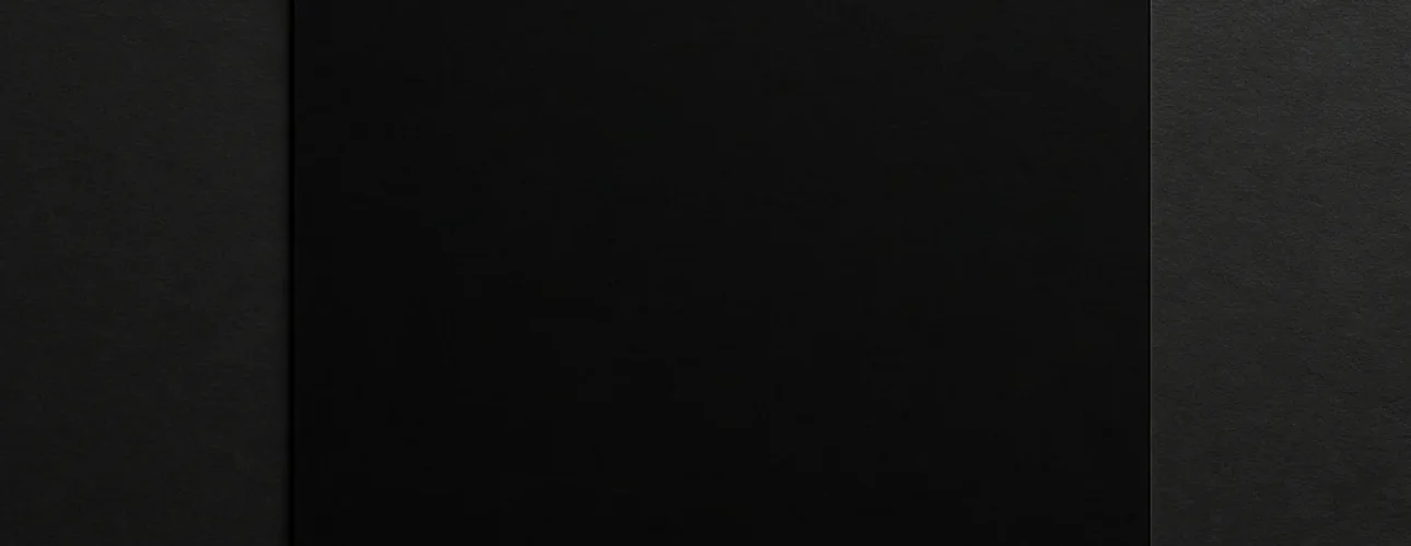 Een vierkant stuk zwart papier gecentreerd op een subtiel gestructureerde, donkere achtergrond creëert een minimalistische en monochrome compositie met subtiele schaduwen, die je uitnodigt na te denken: waar staat de kleur zwart voor?.