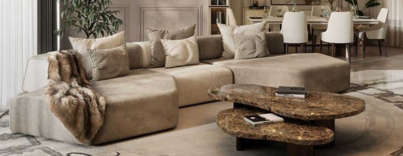 Een luxe woonkamer met een ruime beige hoekbank versierd met sierkussens en een bontdeken. Een unieke gelaagde salontafel staat op een decoratief kleed, terwijl een eethoek met witte stoelen zichtbaar is op de achtergrond.