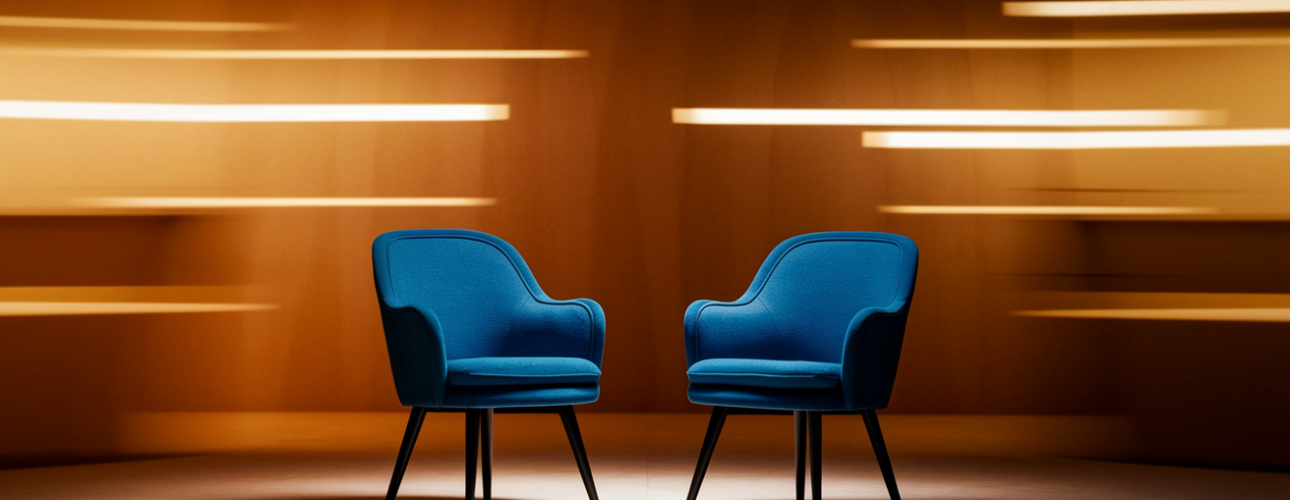 Twee blauwe stoelen staan tegenover elkaar in een warm verlichte ruimte met abstracte gele en oranje lichtstrepen op de achtergrond, waardoor een dramatische en moderne designsfeer ontstaat.